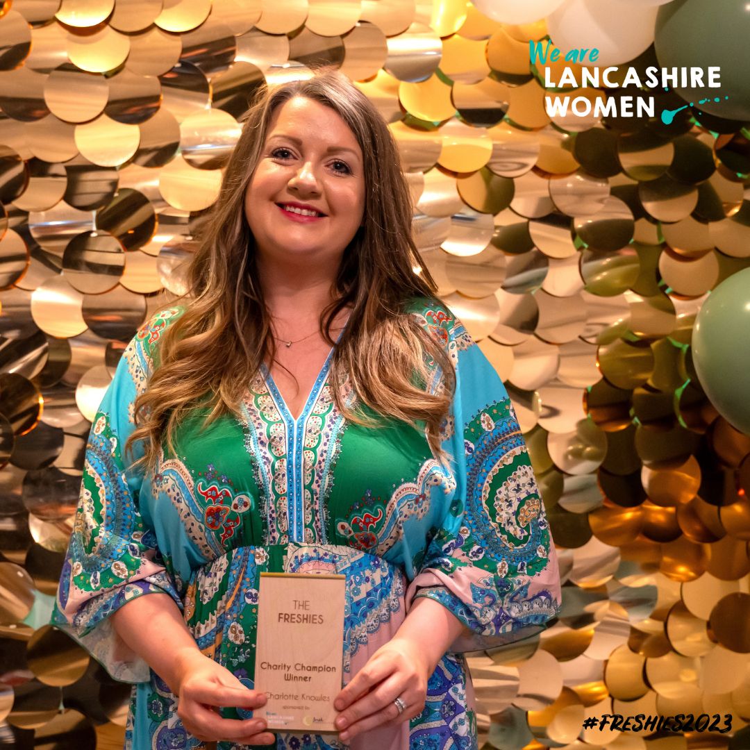 The Charity Champion winner Charlotte Knowles stood in front of a sparkle background and balloons holding her award.