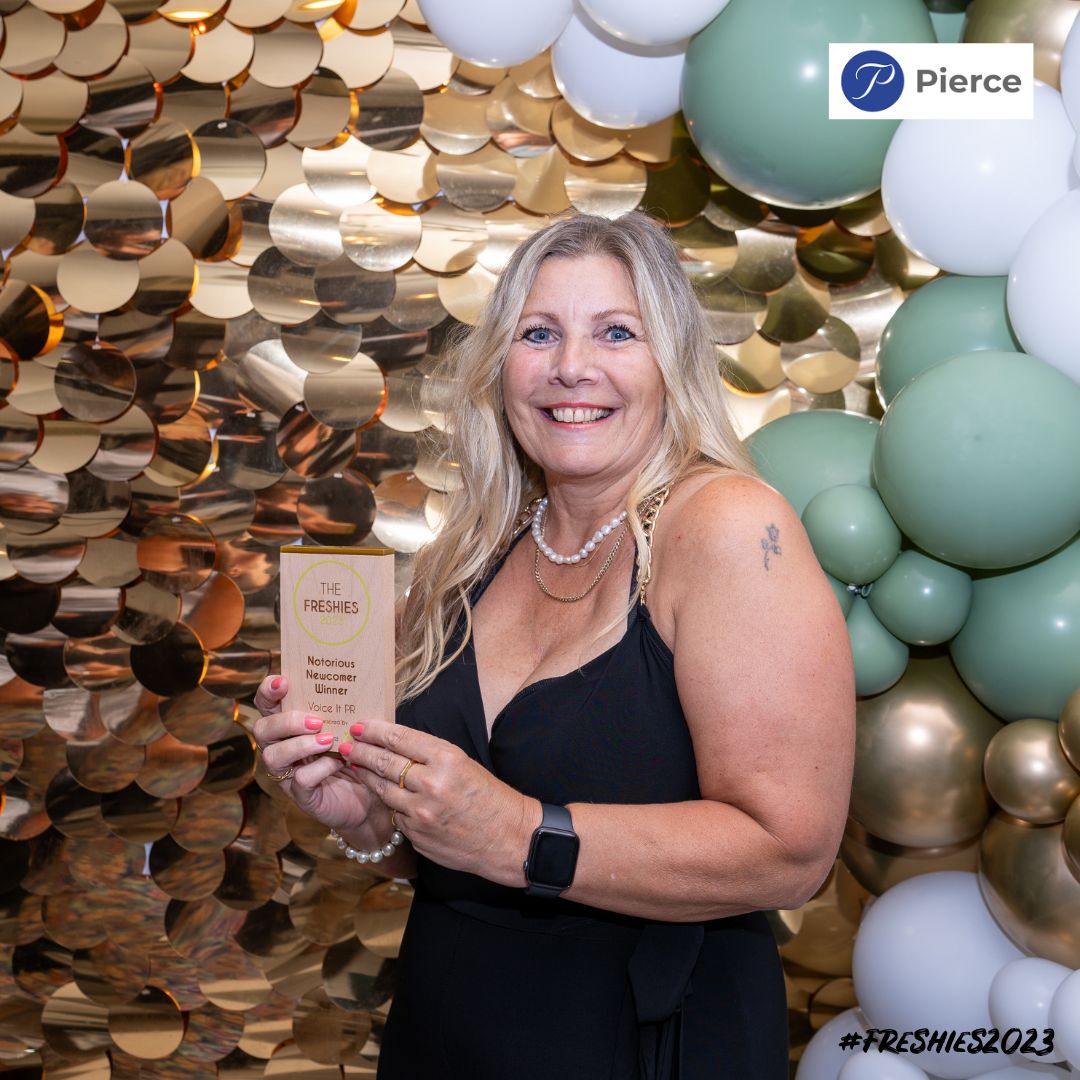 The Notorious Newcomer winner Voice IT PR owner, Kath Lord-Green stood in front of a sparkle background and balloons holding her award.
