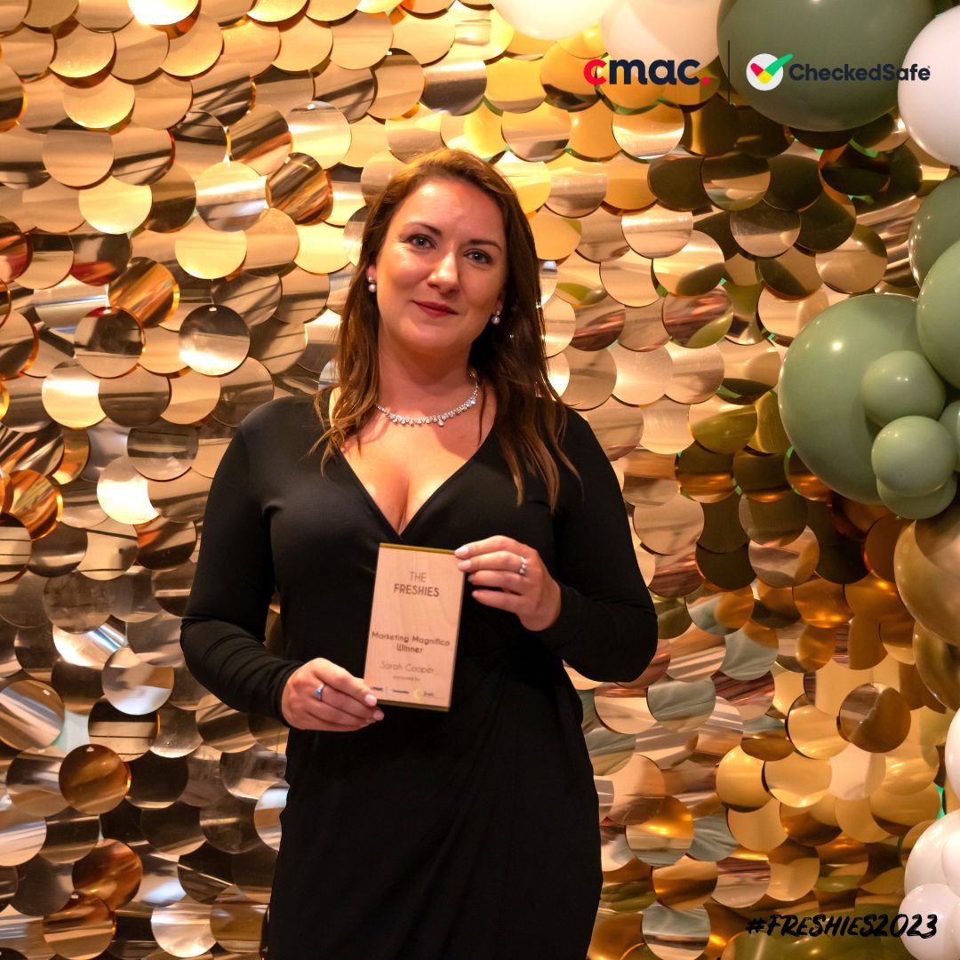 The Marketing Magnifico winner Sarah Cooper stood in front of a sparkle background and balloons holding her award.
